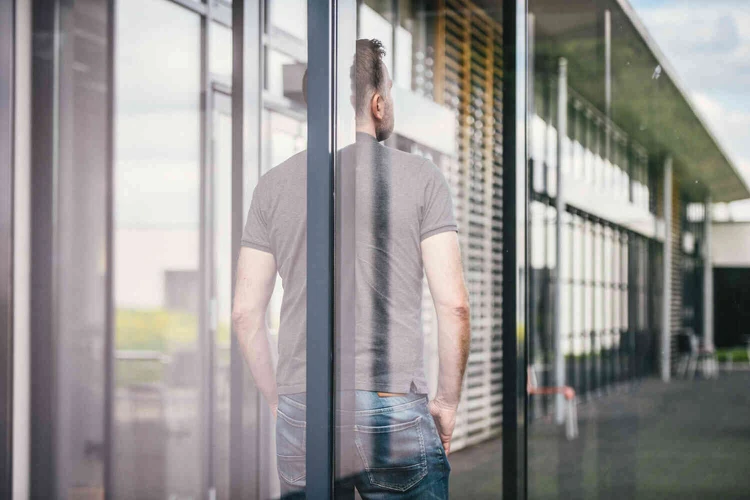 Mann steht mit dem R&uuml;cken zum Fenster