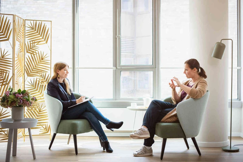 Therapeuting spricht mit patientin im gro&szlig;en raum, beide sitzen gegen&uuml;ber